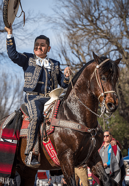 Picture of Manuel Enrique riding a dancing horse while tipping his sombrero to the crowd