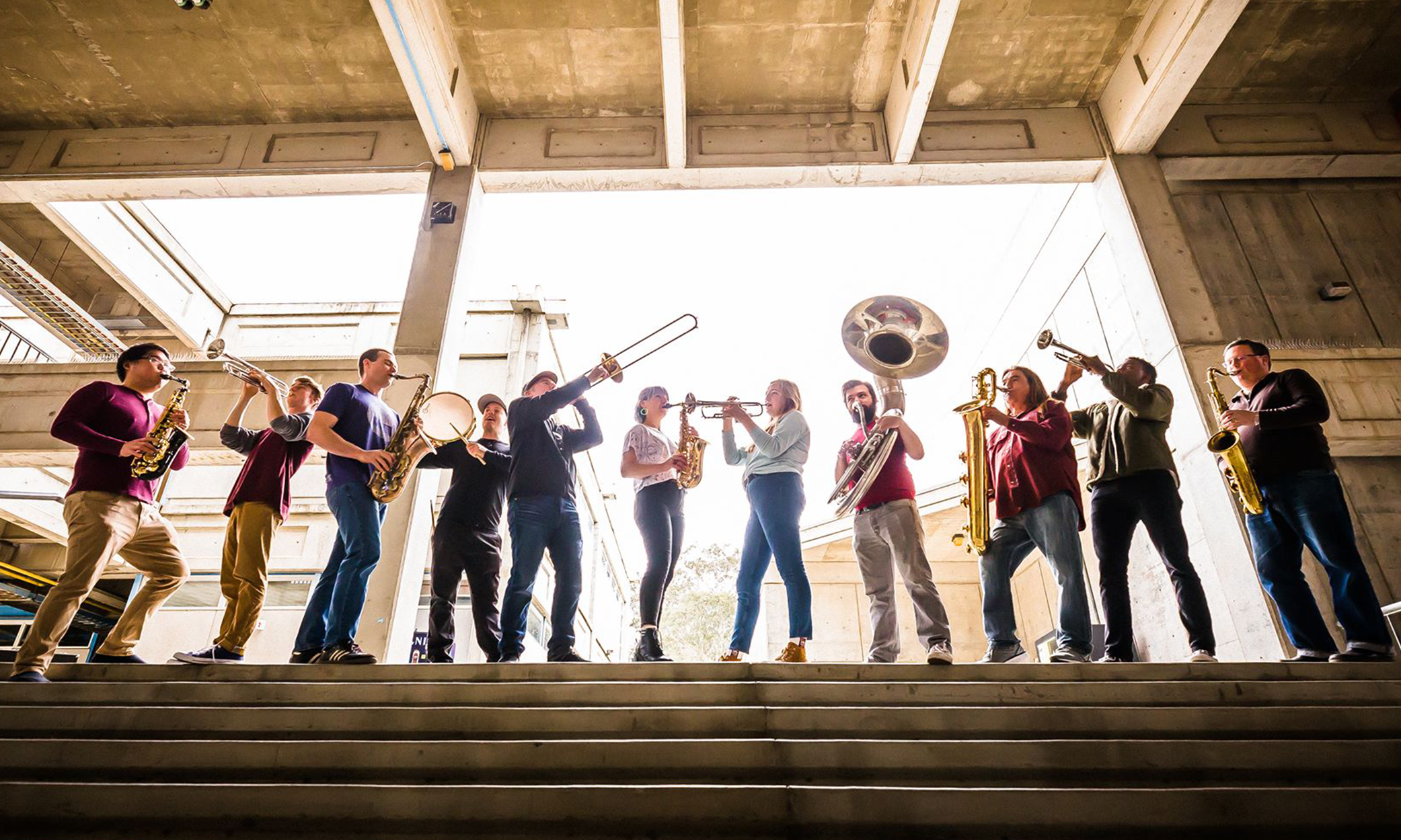 Image of band holding and playing a variety of brass instruments.